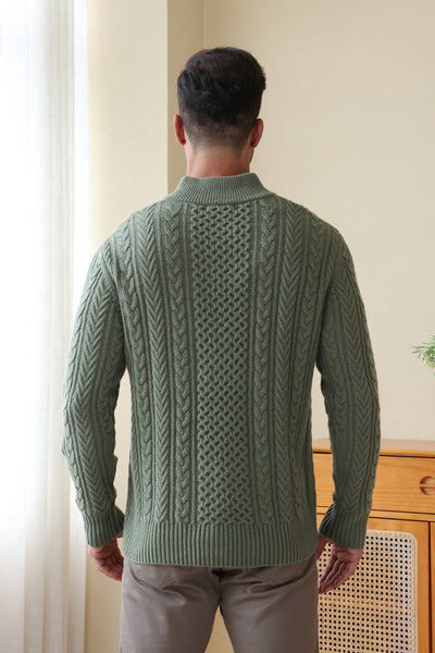 Man wearing a green Aran cable knit sweater by Inis Aran#color_boxwood